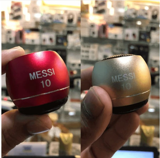 Two small cylindrical speakers, one red and one gold, with 'Messi 10' branding held in a hand.