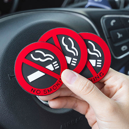 Three red 'No Smoking' stickers held over a car dashboard.